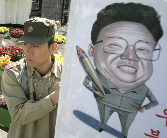 A former South Korean intelligence agent wearing North Korean military uniform stands next to a picture of North Korean leader Kim Jong Il as he says he wants to go to North Korea to destroy the North ...