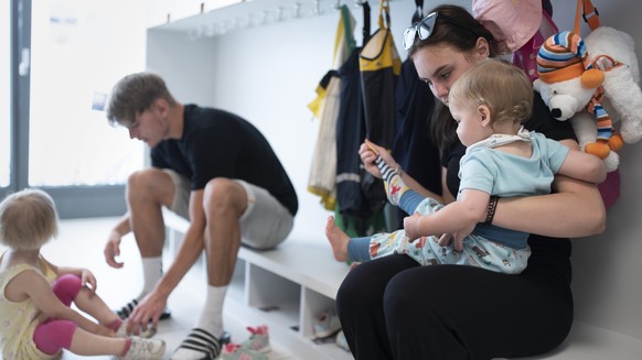 THEMENBILD ZUR LANCIERUNG DER KITA-INITIATIVE --- Betreuungspersonal hilft Kleinkindern beim Anziehen der Schuhe und Sonnenschutzkleidung, bevor es zum Spielen in den Aussenbereich der Kita 6a der Sti ...